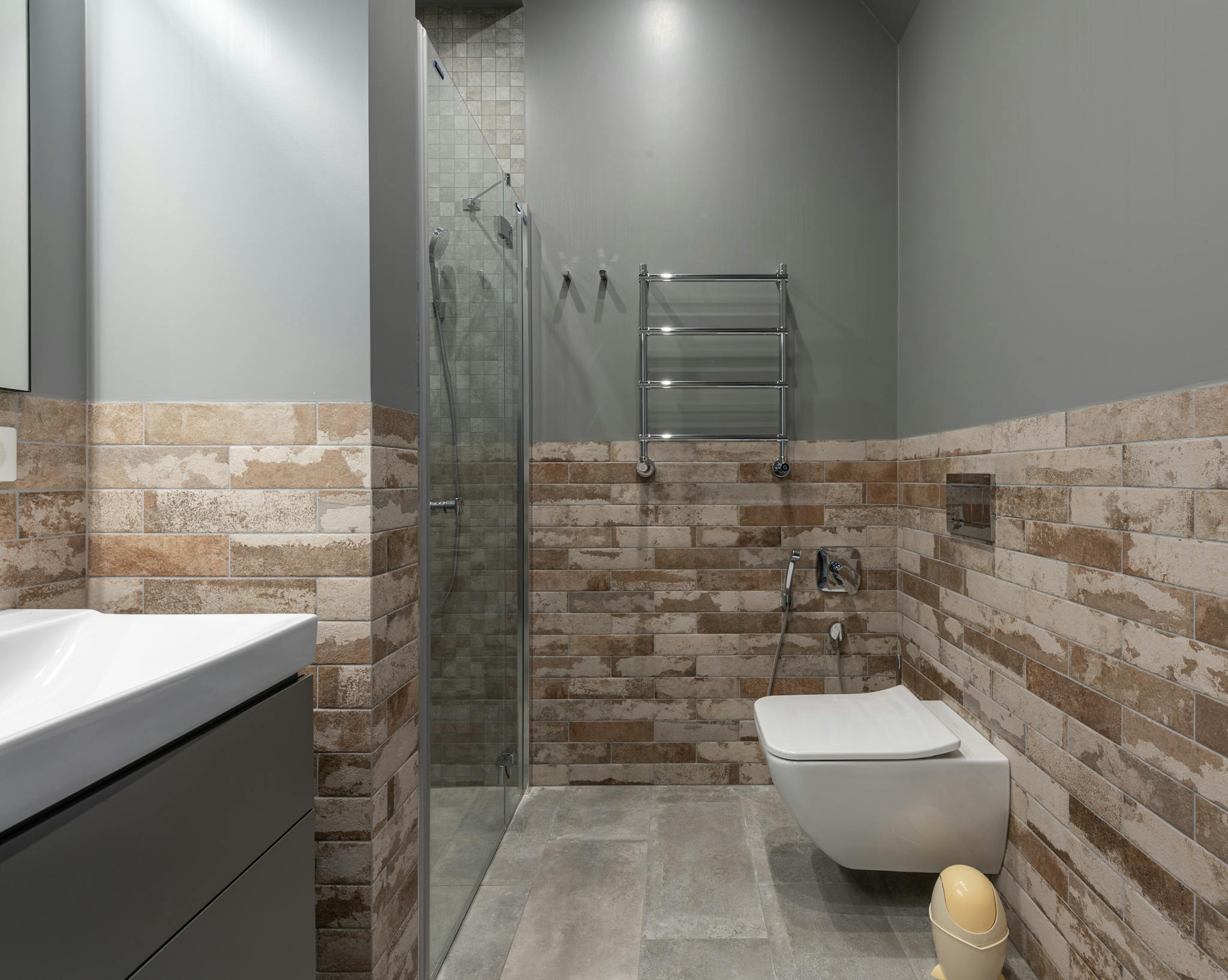 Stylish contemporary bathroom featuring a glass shower and brick accent wall.